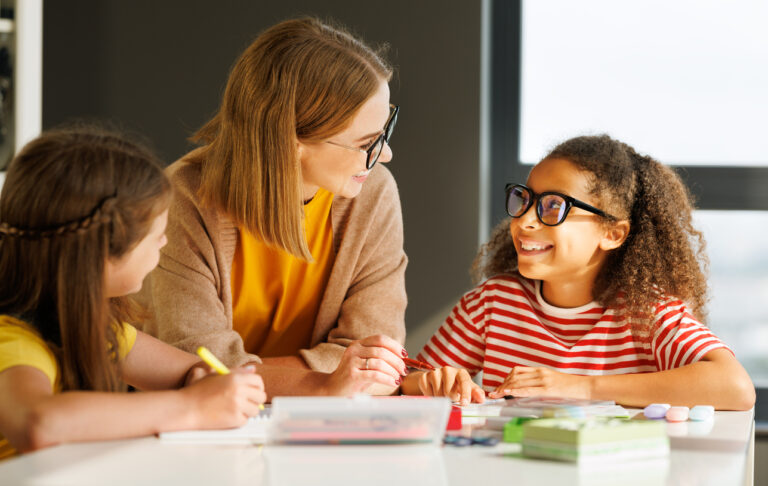 female teacher helping 4th and 5th grade students during class lesson